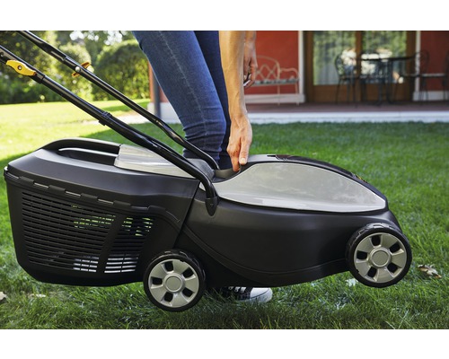 Eine Person bedient einen Rasenmäher auf einer Rasenfläche.