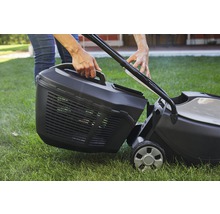 Person befestigt Grasfangkorb an Rasenmäher