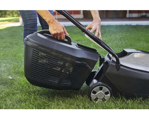 Person befestigt Grasfangkorb an Rasenmäher