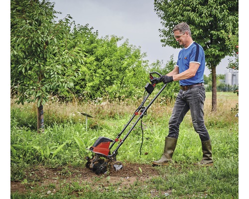Un homme travaille avec une motobineuse dans le jardin.
