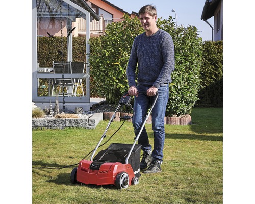 Mann benutzt einen Rasenlüfter im Garten.