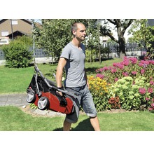 Un homme transporte un scarificateur dans le jardin
