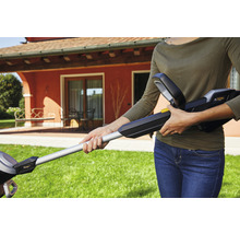 Frau bedient Akku-Heckenschere im Garten.