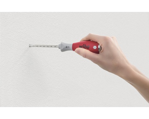 Une main tient un tournevis à butée de profondeur Wiha contre un mur.