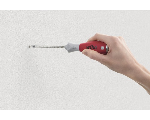 Une main visse une vis dans le mur avec un tournevis Wiha.