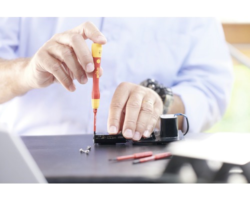 Handwerker arbeitet mit Schraubendreher an elektronischem Gerät