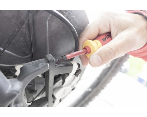 Eine Person benutzt einen Schraubendreher an einem Fahrrad.