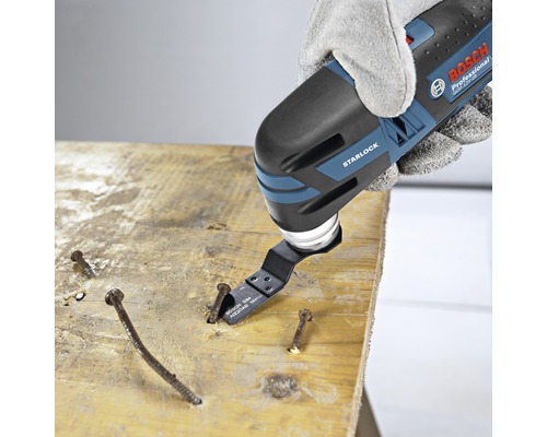 Outil électrique oscillant travaillant une planche de bois avec des clous