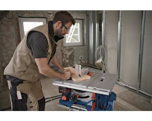 Artisan utilisant une scie circulaire de table pour couper du bois dans une construction brute.