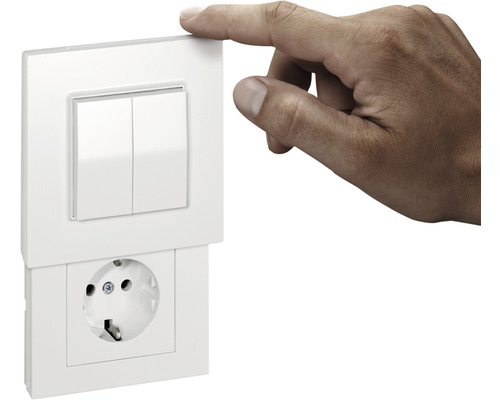 Aufnahme einer Person, die einen Lichtschalter über einer Steckdose bedient