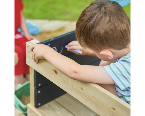 Junge malt mit Kreide auf einer Tafel an einem Sandkasten