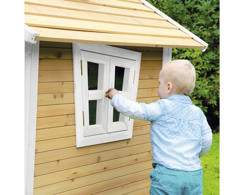 Kind spielt an einem Holzspielhaus mit Fenster