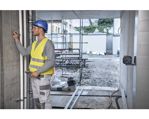 Artisan avec niveau laser sur un chantier