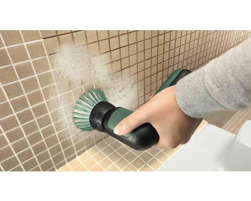 Eine Person reinigt Fliesen mit einer elektrischen Reinigungsbürste