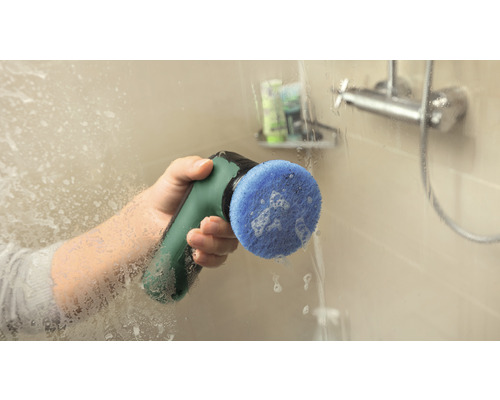 Eine Person reinigt eine Duschwand mit einer elektrischen Reinigungsbürste.