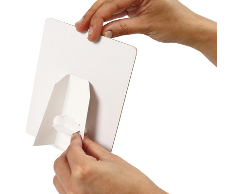 Person montiert einen weißen Aufsteller auf der Rückseite einer weißen Platte.