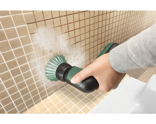 Une personne nettoie des carreaux avec une brosse électrique.