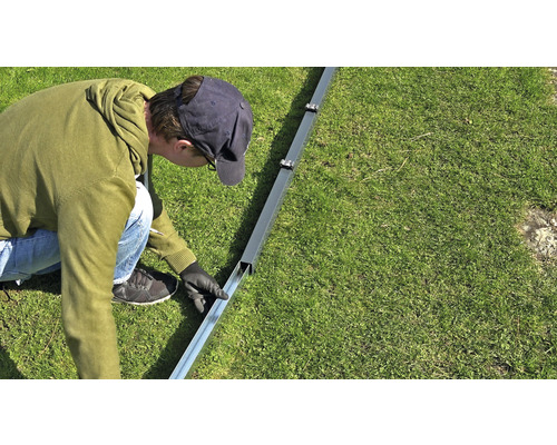 Une personne monte une structure métallique dans le jardin.
