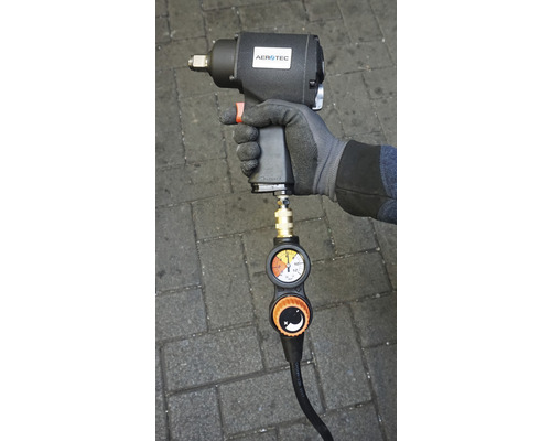 Druckluft-Schlagschrauber mit Manometer in der Hand