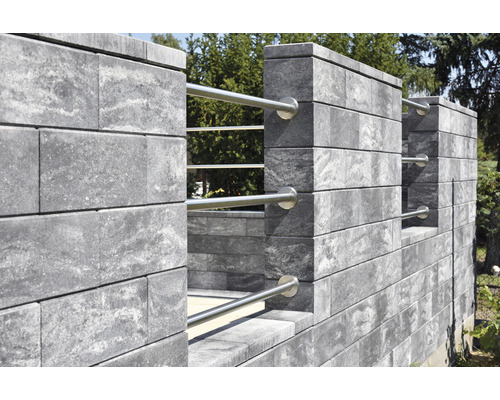 Mur gris en pierres de béton avec éléments métalliques dans le jardin