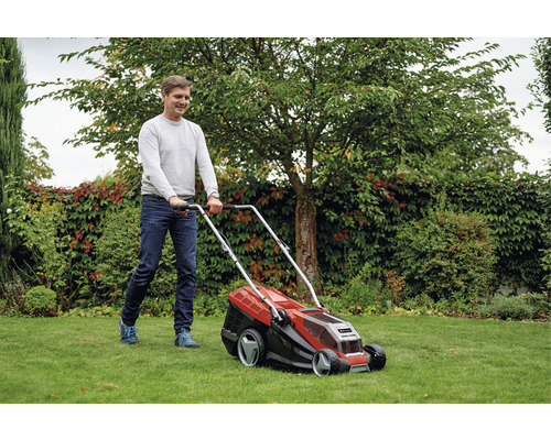 Un homme tond la pelouse avec une tondeuse à gazon dans le jardin.