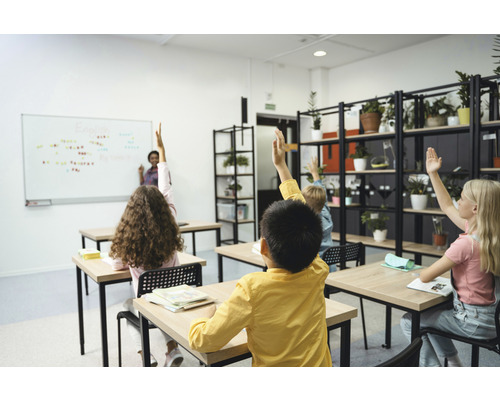 Salle de classe avec des élèves qui lèvent la main pendant le cours