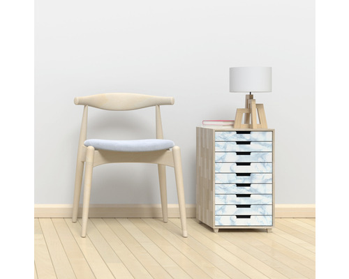 Scène avec une chaise en bois, un meuble à tiroirs à l''aspect marbré, une lampe et un livre