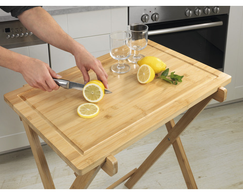 Serviertisch aus Bambus mit Schneidebrett und Person, die Zitrone schneidet