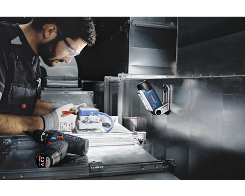 Handwerker bei der Arbeit mit Akku-Bohrschrauber, Lampe und Werkzeug