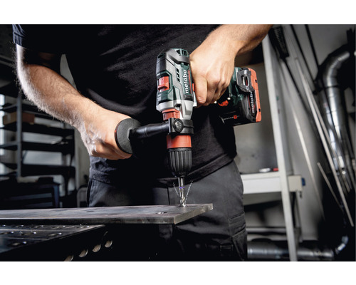 Ein Mann bohrt mit einer Metabo Bohrmaschine durch ein Metallstück.