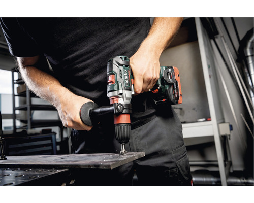 Eine Person bohrt mit einer Metabo Akku-Bohrmaschine ein Loch in ein Metallstück.