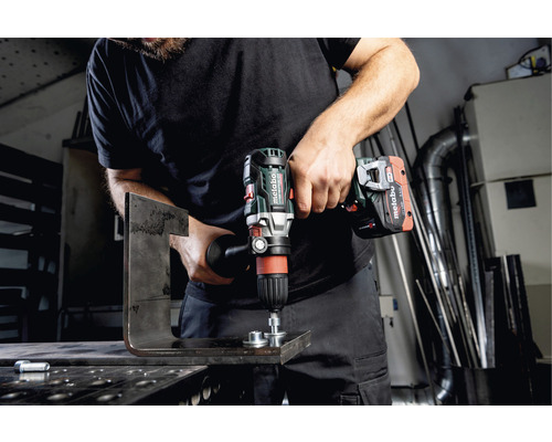 Ein Mann bohrt mit einem Akku-Bohrschrauber von Metabo ein Metallstück.