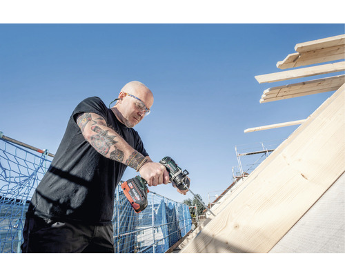 Un artisan travaille sur un toit en bois avec une visseuse sans fil