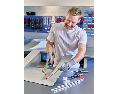 Homme soudant une tôle avec des accessoires de soudure dans un atelier