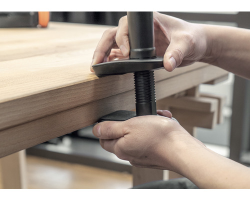 Une personne fixe un support de table sur un plateau de table
