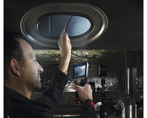 Ein Mann untersucht mit einer Inspektionskamera einen Lüftungsschacht.