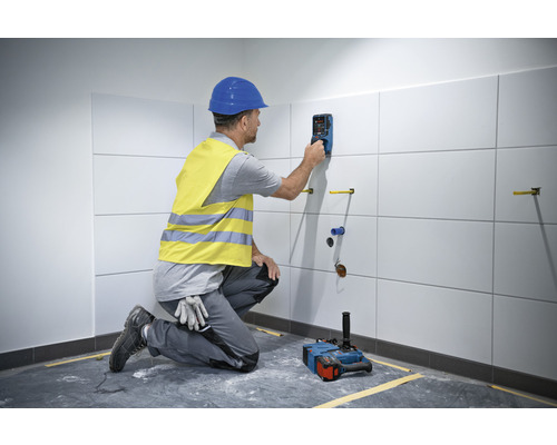 Handwerker nutzt ein Ortungsgerät an einer gefliesten Wand in einem Badezimmer.