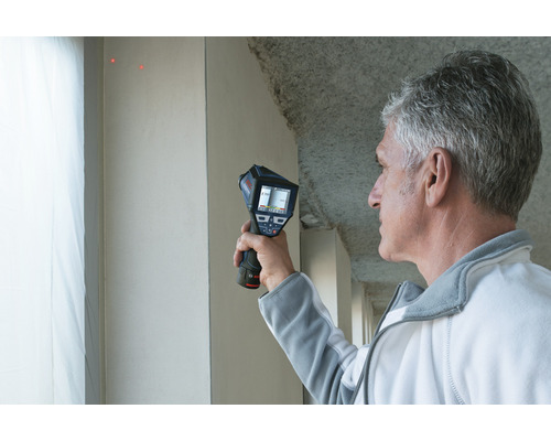 Mann verwendet eine Wärmebildkamera zur Inspektion einer Wand.