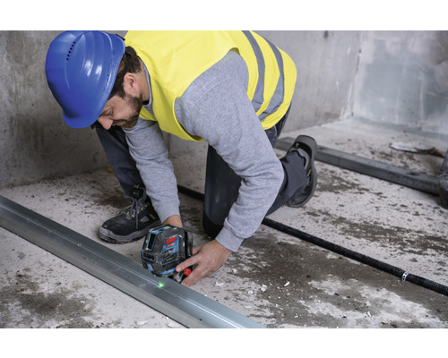 Handwerker mit Laser-Wasserwaage zur Ausrichtung einer Metallschiene