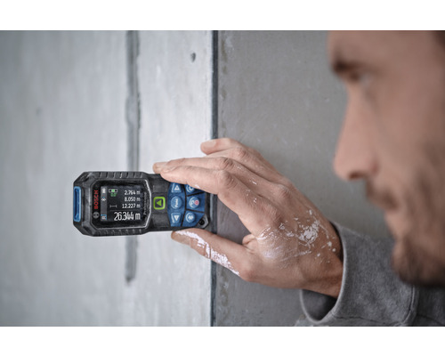 Une personne utilise un télémètre laser Bosch pour effectuer des mesures.