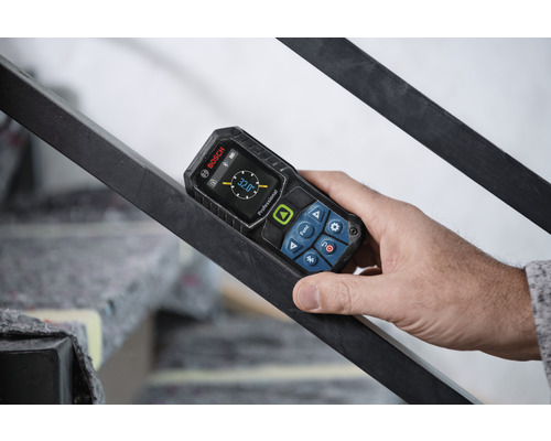 Une main tient un inclinomètre numérique Bosch sur une rampe