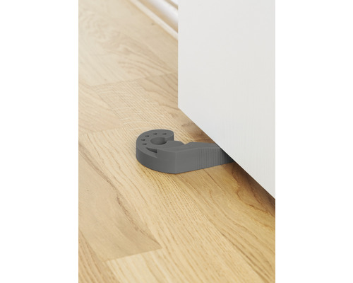 Grauer Türstopper aus Gummi vor einer Tür auf einem Holzboden