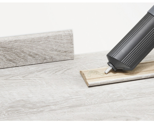 Fixation d''une plinthe en bois avec de la colle provenant d''un pistolet à cartouche