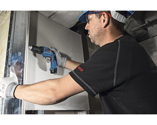 Handwerker befestigt Gipskartonplatte mit einem Akku Trockenbauschrauber