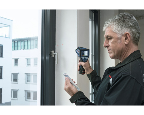 Mann verwendet eine Wärmebildkamera zur Analyse eines Fensters.