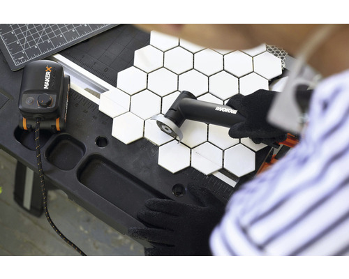 Une personne coupe des carreaux hexagonaux avec un coupe-carreaux sur un établi.