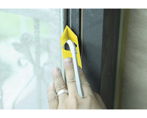 Main enfonçant une bande d''étanchéité dans un cadre de fenêtre avec un outil de jointoiement