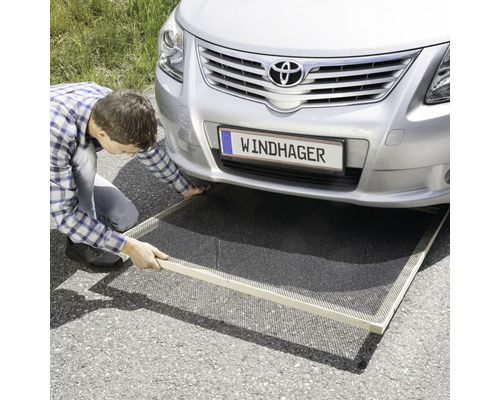 Mann verlegt Windhager Unkrautvlies unter einem Auto