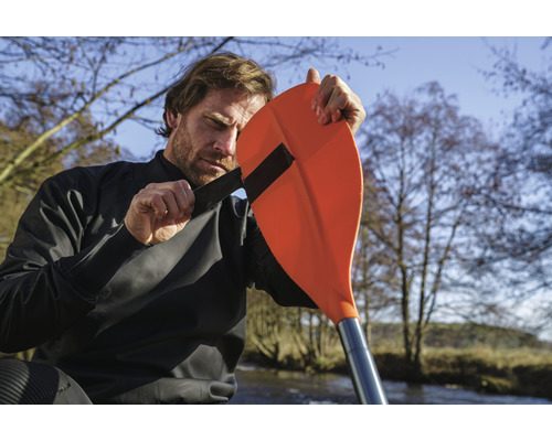 Un homme fixe une pagaie à une combinaison sèche de kayak pour les sports nautiques de plein air
