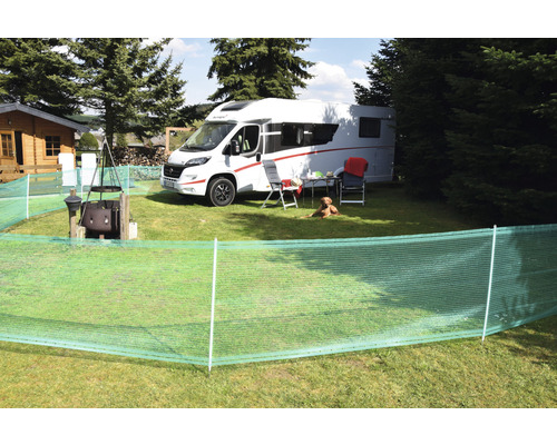 Scène de camping avec caravane, brise-vue, meubles et chien